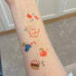 Summer-themed temporary tattoo sticker collection – 25×20mm colourful illustrations including animals, beach elements, food, and celestial icons by TIDES.